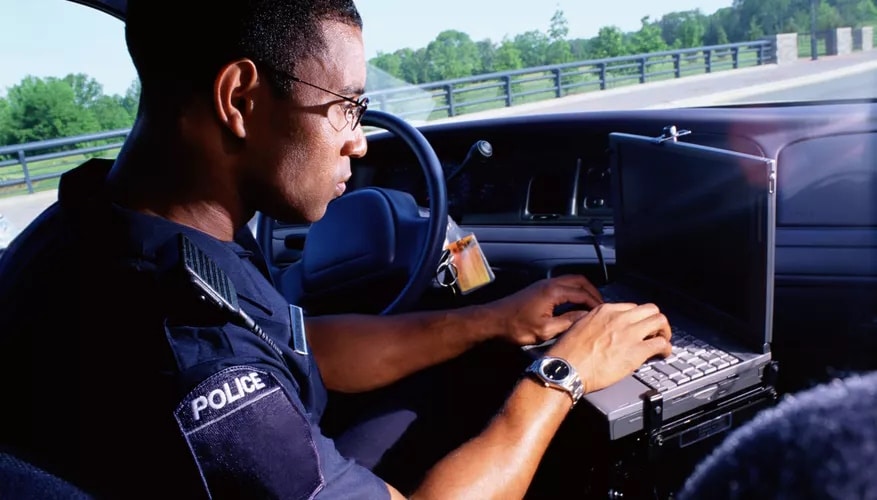 Police officer using a computer in police car