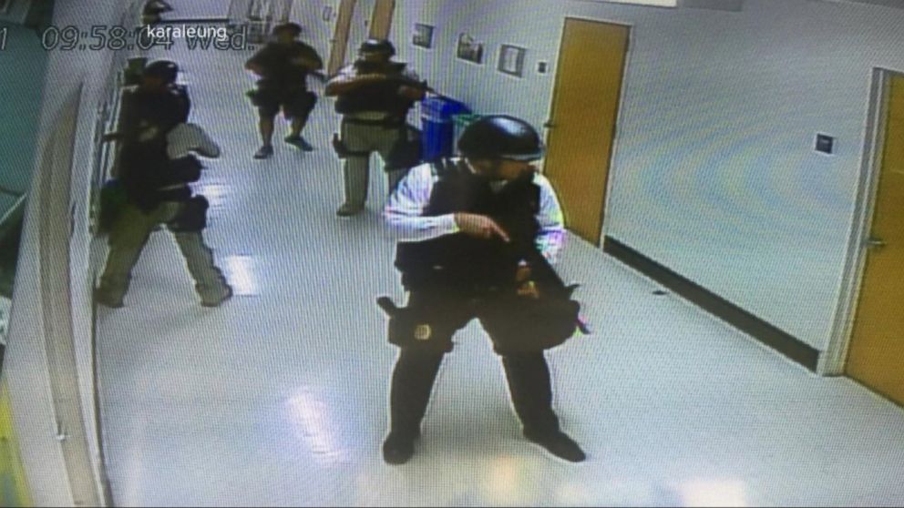 A police officer swiftly walks down a hallway, prepared to hide, run, or fight in an active shooter response.