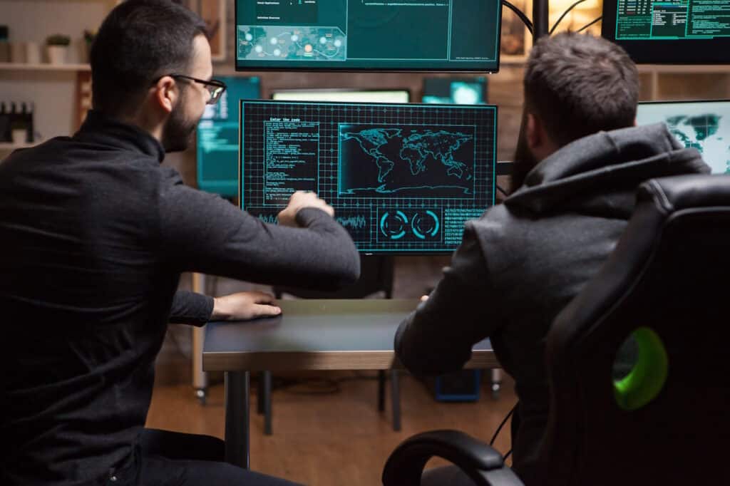 Two men sitting at a desk looking at a computer screen as they discuss and develop a Cybersecurity Incident Response Plan.